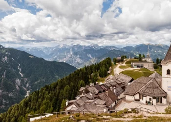 Das Wallfahrtsdorf Monte Lussari mit dem Kirchturm des Santuario und dem Panorama der Julischen Alpen