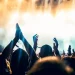 Publikum mit erhobenen Händen vor einer hell beleuchteten Konzertbühne