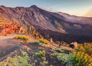 Vulkanlandschaft des Ätna mit Lavagestein und rauchendem Gipfelkrater bei Catania, Sizilien