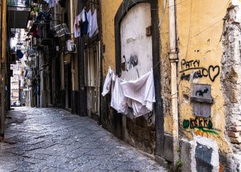 Spaccanapoli: enge Kopfsteinpflaster-Gasse in Neapels Altstadt mit trocknender Wäsche, verwitterter Fassade und Graffiti. Foto: George Piskov / Pexels