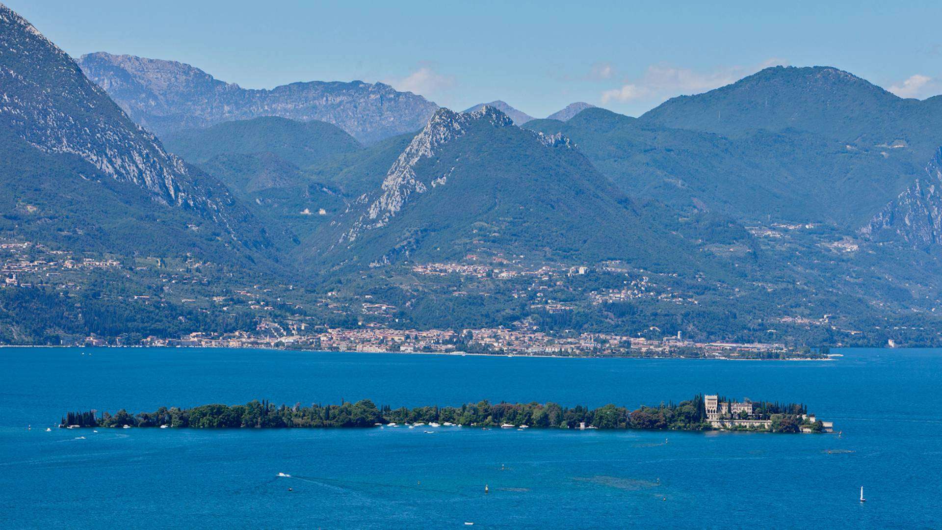 Die bewaldete Isola del Garda mit ihrer neugotischen Villa vor den Bergen des Westufers