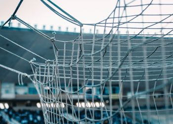 Nahaufnahme eines Fußball-Tornetzes vor den leeren Sitzreihen eines Stadions