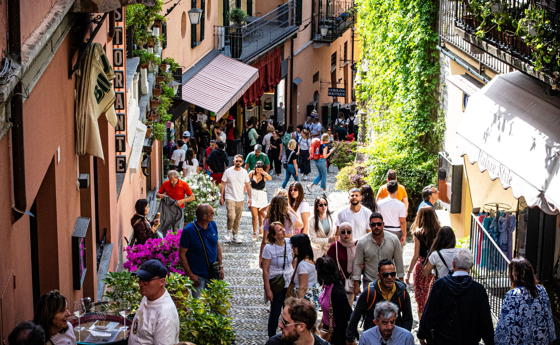 Bellagio – Gasse in der Altstadt Besucher in einer engen Gasse der Altstadt von Bellagio mit Läden und Blumen