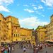 Der Campo de' Fiori in Rom mit Menschen vor den Cafés und den ockerfarbenen Häuserfassaden