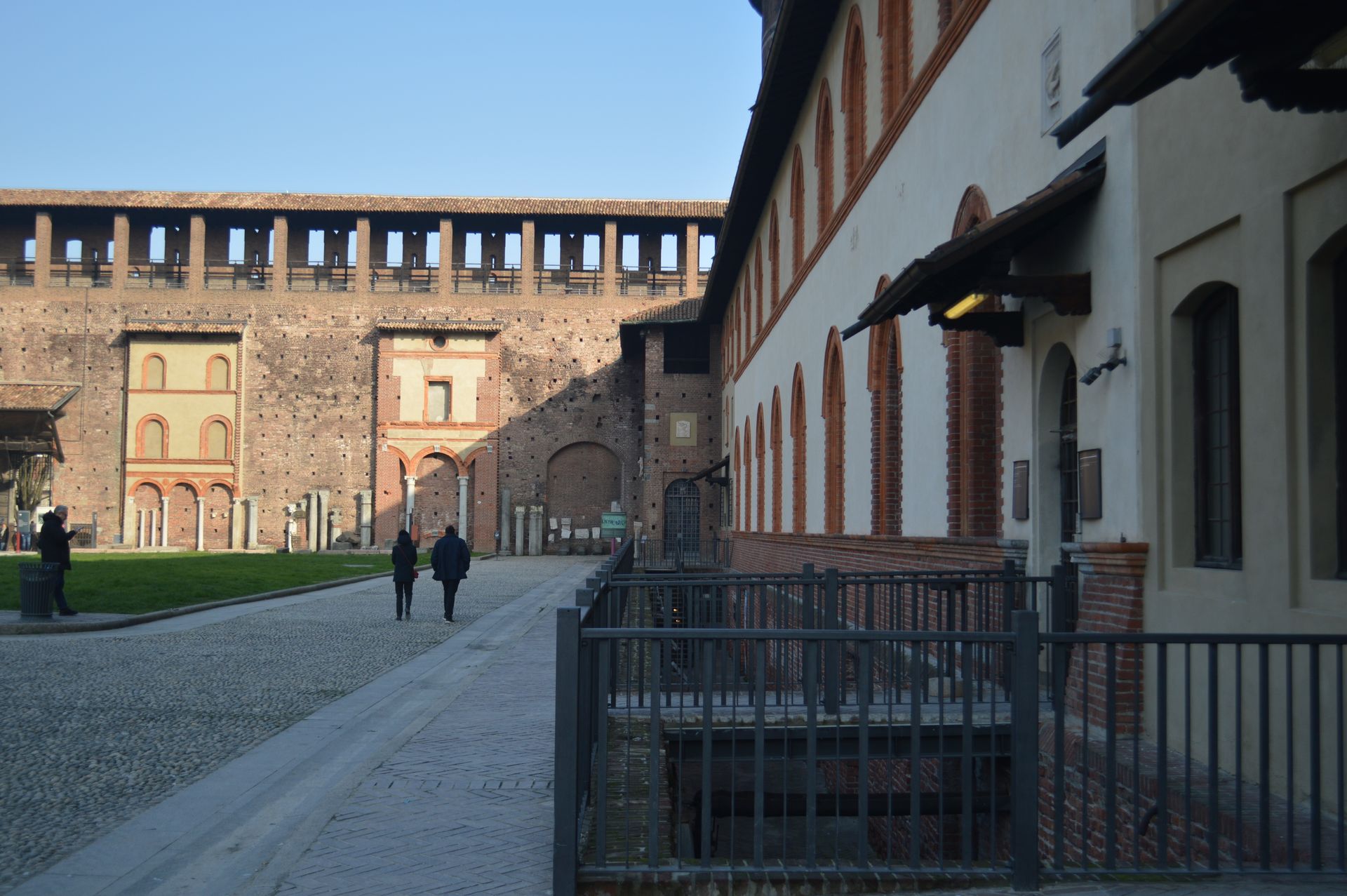 Backsteinmauern und Innenhof des Castello Sforzesco in Mailand mit Spaziergängern