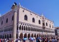 Die weiß-rosa Südfassade des Dogenpalasts in Venedig mit gotischer Loggia und Besuchern davor