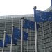 Blaue EU-Flaggen vor der Glasfassade des Berlaymont-Gebäudes der Europäischen Kommission in Brüssel