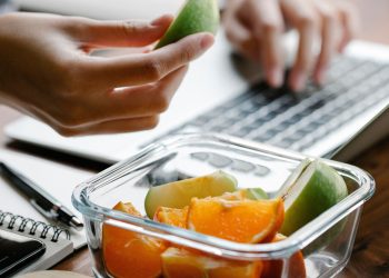 Eine Auswahl an frischem Obst, Gemüse, Vollkornbrot und Nüssen als gesunde Snacks für Schule und Beruf.