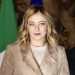 Giorgia Meloni im beigefarbenen Blazer vor italienischer und europäischer Flagge sowie historischen Wandteppichen