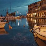 Beleuchtete Häuser und Boote im Hafen von Lazise bei Nacht