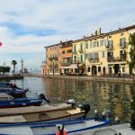 Bunte Häuserzeile und Boote im Hafen von Lazise am Ostufer des Gardasees