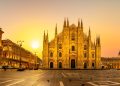 Die gotische Marmorfassade des Mailänder Doms im goldenen Licht der aufgehenden Sonne über der leeren Piazza del Duomo