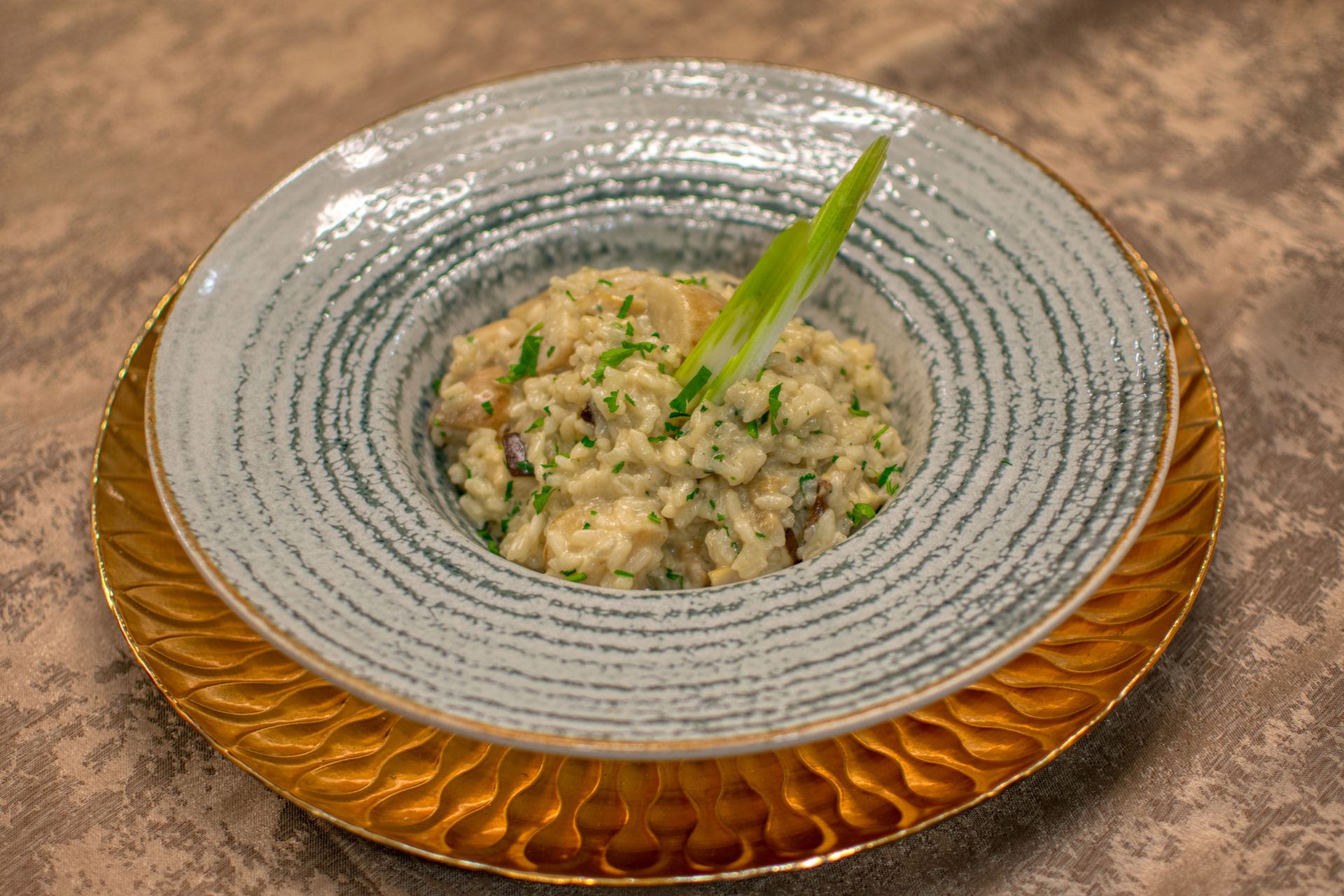 Risotto – cremig angerichtet Cremiges Risotto mit Kräutern auf einem gemusterten Teller angerichtet