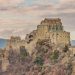Die Abtei Sacra di San Michele auf ihrem Felsgrat im warmen Abendlicht, dahinter die Berge des Val di Susa