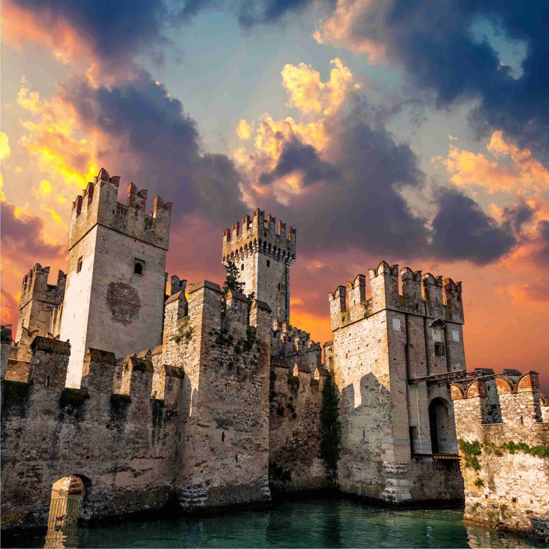 Das Castello Scaligero von Sirmione im warmen Abendlicht über dem Wasser