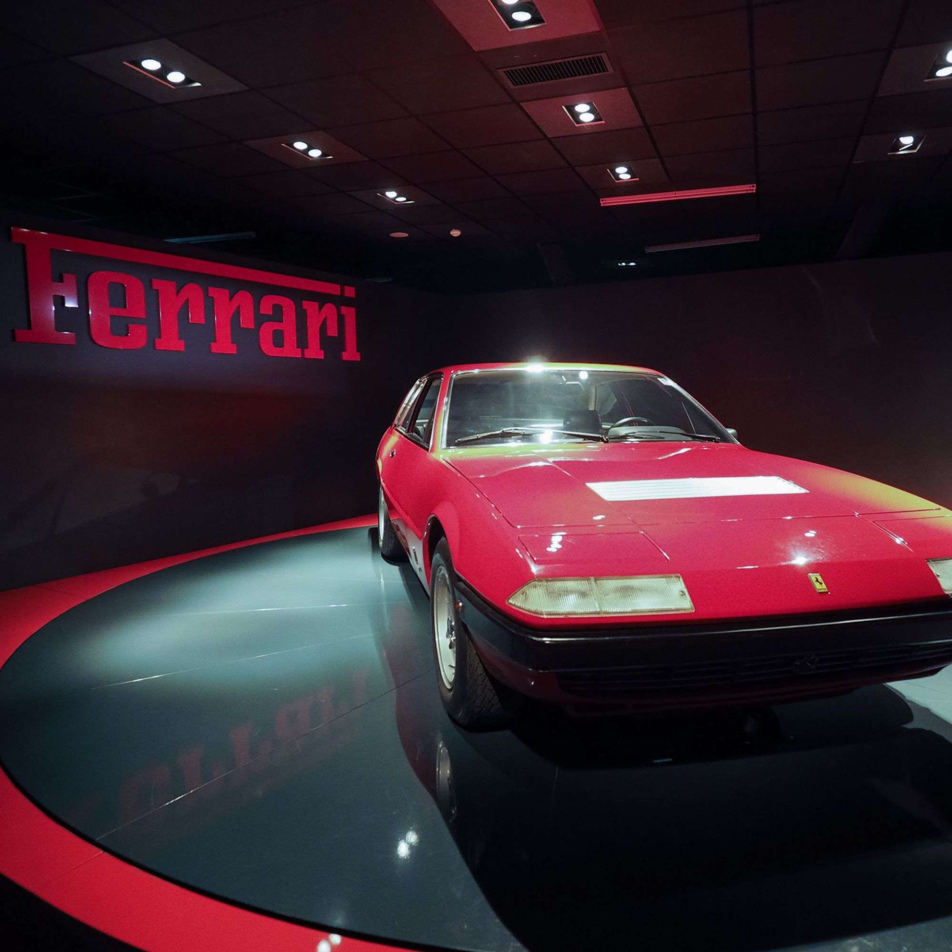 Roter Ferrari im Automobilmuseum Roter Ferrari vor einer roten Wand mit Ferrari-Schriftzug in einem Automobilmuseum