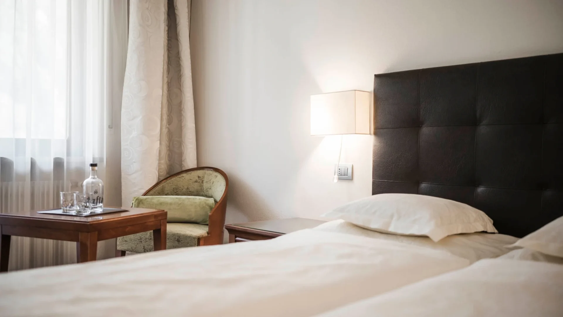 Doppelzimmer mit dunklem Lederkopfteil, Sessel und Fensterplatz im Romantik Hotel Stafler