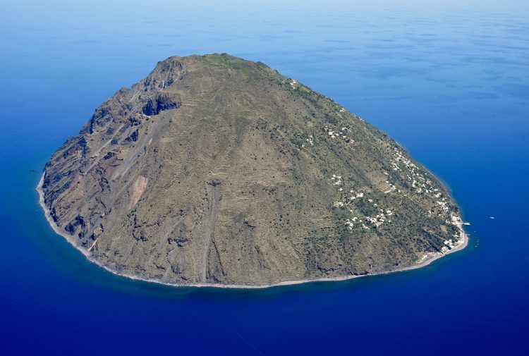 Die Insel Alicudi mit steilen Hängen und Küstensiedlung im blauen Tyrrhenischen Meer, von Süden aus der Luft gesehen