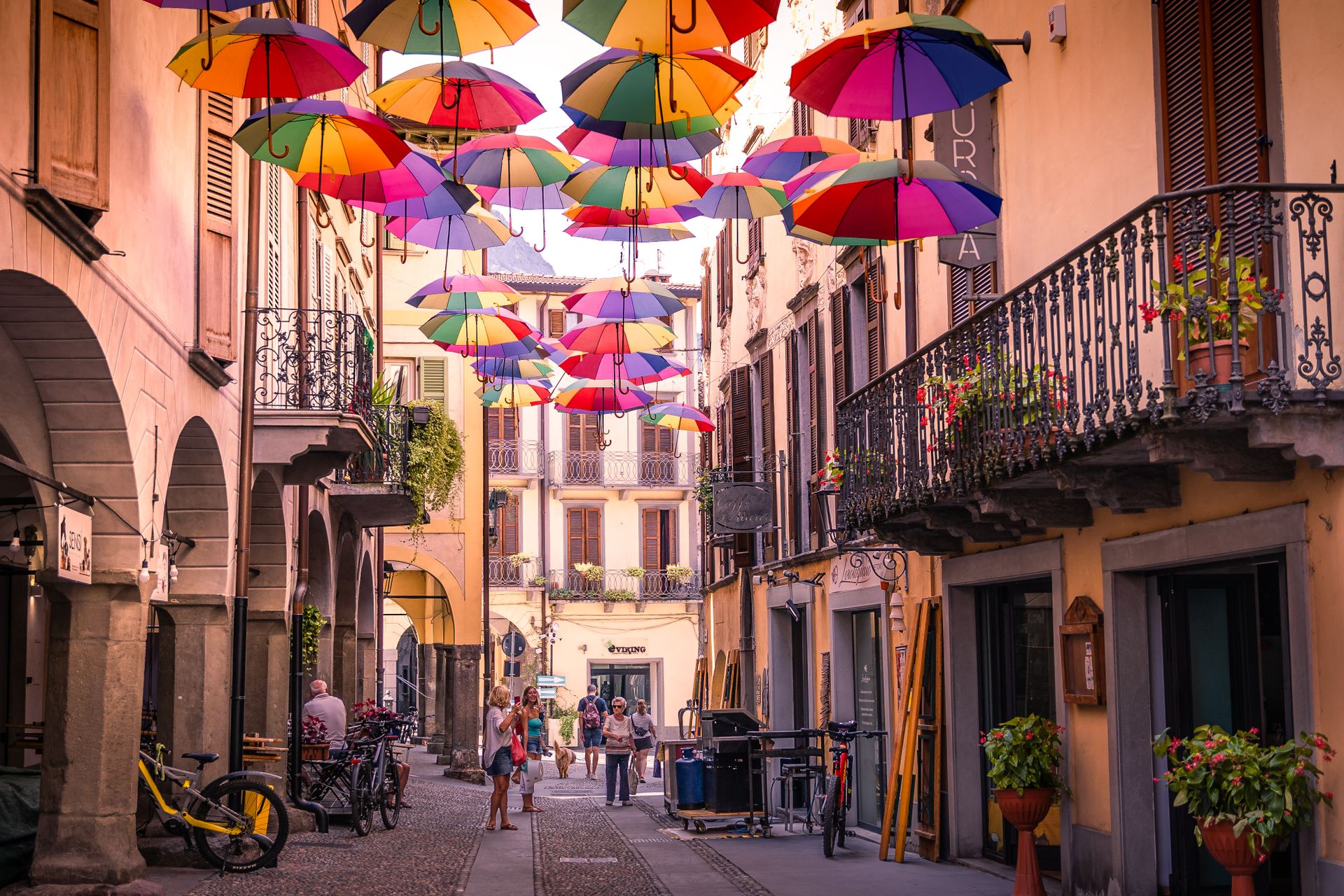 Bunte Schirme über einer Altstadtgasse Bunte Regenschirme über einer Altstadtgasse mit Arkaden und schmiedeeisernen Balkonen
