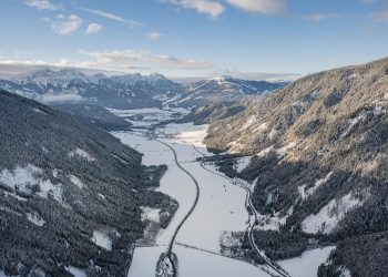 Luftbild des verschneiten Antholzertals mit Wäldern, Wiesen und schneebedeckten Bergen