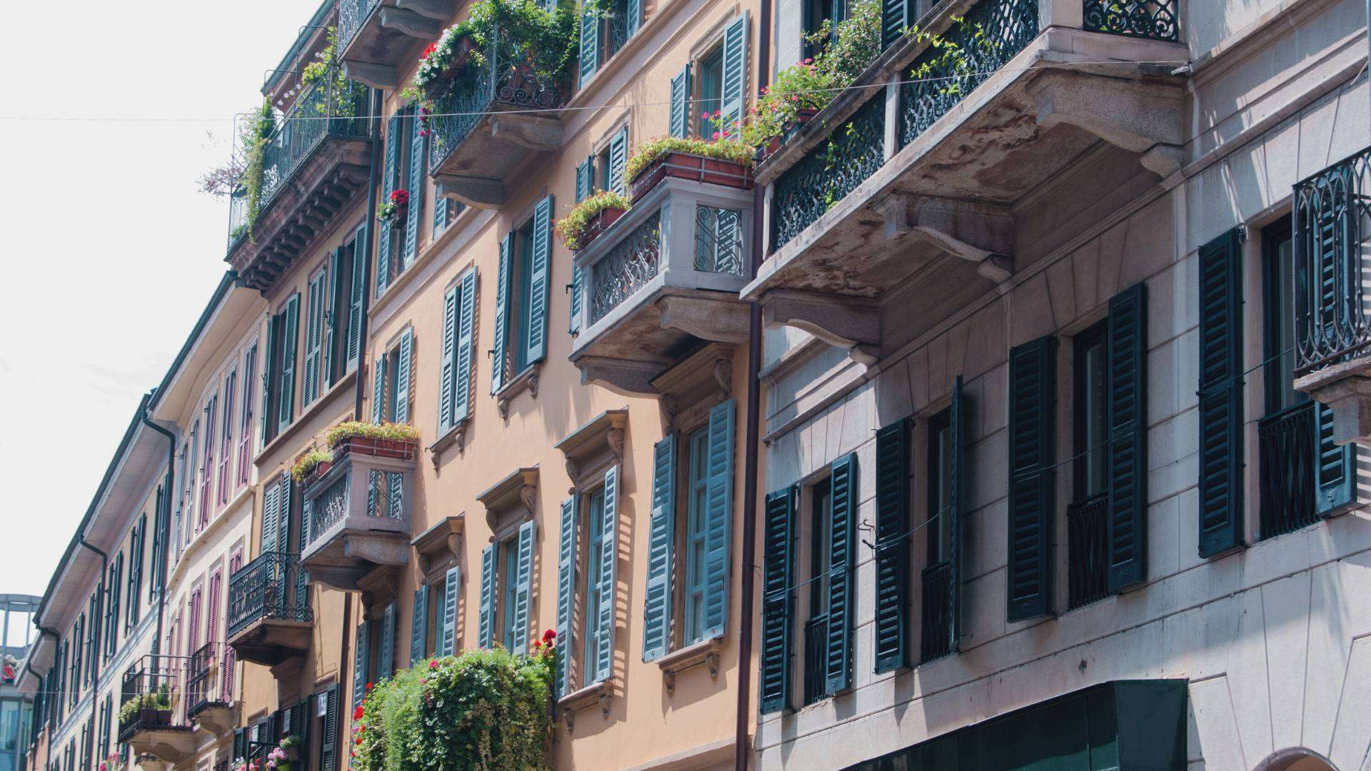 Hausfassaden mit Balkonen, grünen Fensterläden und Pflanzen in einer Straße des Viertels Brera in Mailand