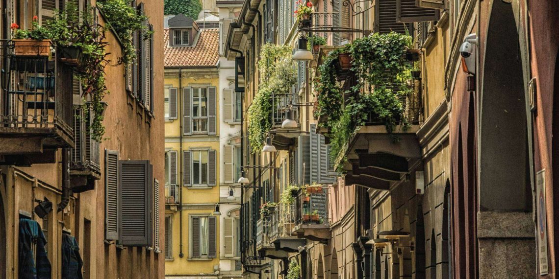 Schmale Gasse in Brera in Mailand zwischen ockerfarbenen Häusern mit Fensterläden und begrünten Balkonen