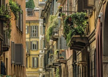 Schmale Gasse in Brera in Mailand zwischen ockerfarbenen Häusern mit Fensterläden und begrünten Balkonen