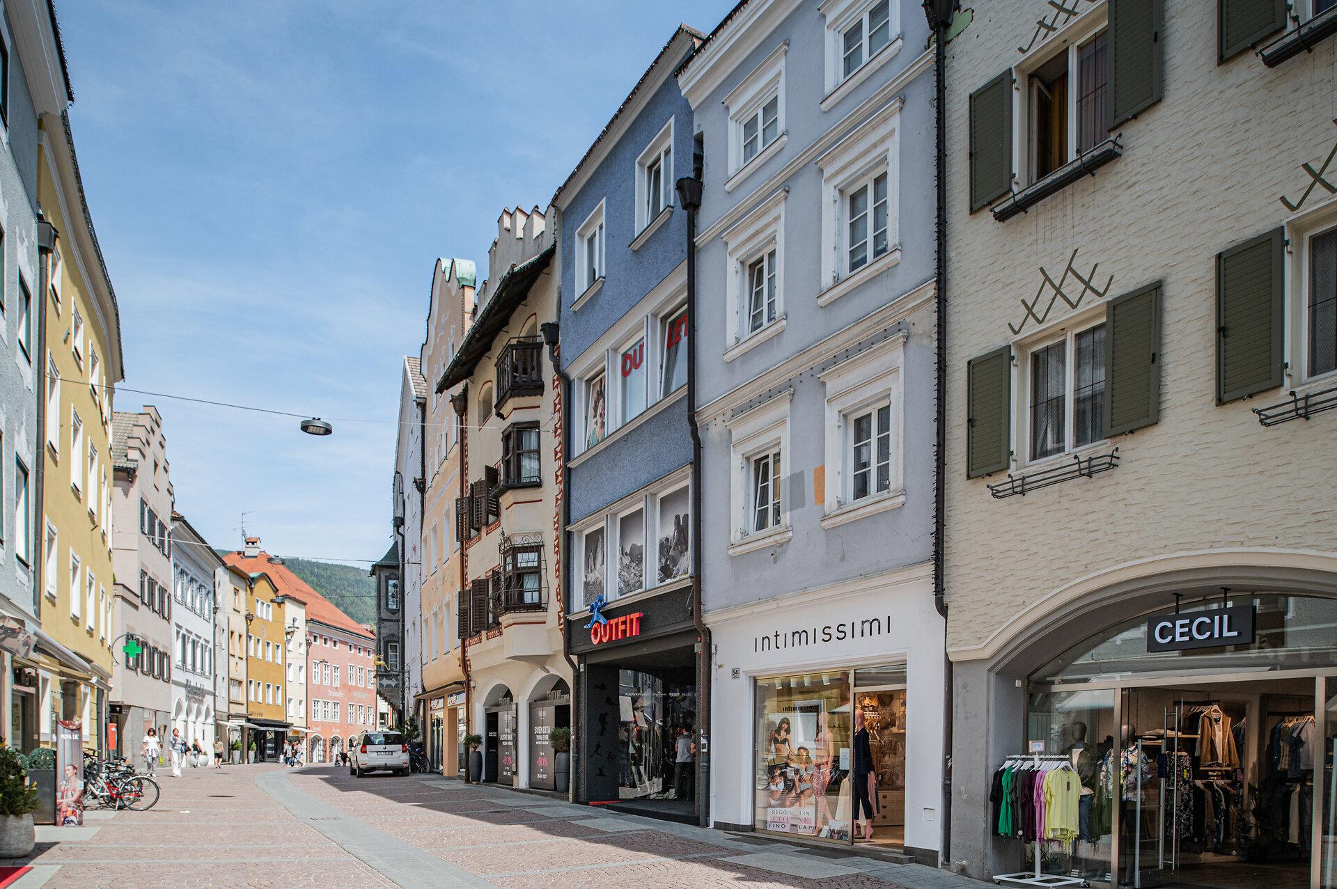 Bunte Bürgerhäuser mit Erkern und Geschäften in der Brunecker Stadtgasse an einem Sommertag
