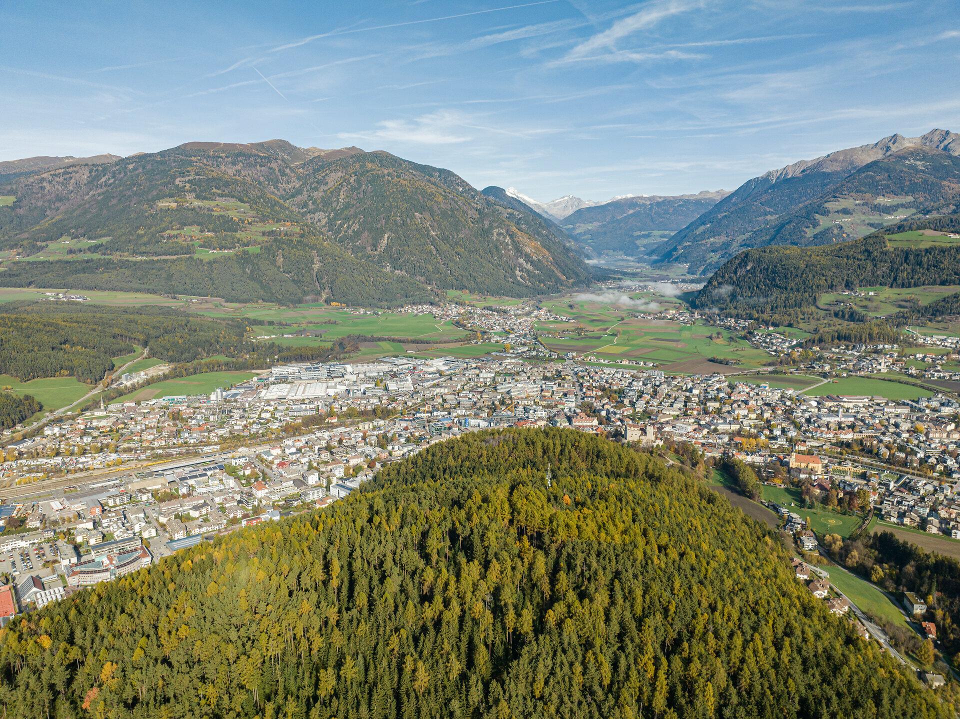 Luftblick über den Brunecker Talkessel im Pustertal mit der Stadt, Wäldern und den Bergen im Hintergrund