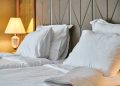 Ein Hotelzimmer mit weiß bezogenem Bett und warmer, gedämpfter Beleuchtung