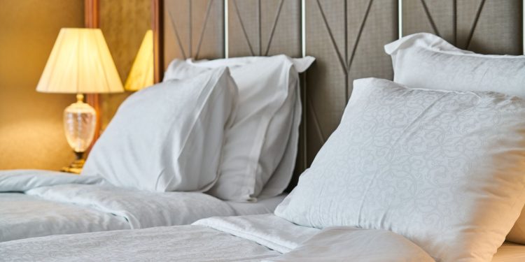 Ein Hotelzimmer mit weiß bezogenem Bett und warmer, gedämpfter Beleuchtung