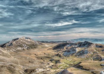 Weite, kahle Hochebene von Campo Imperatore mit den Bergkämmen des Gran-Sasso-Massivs unter Wolkenhimmel