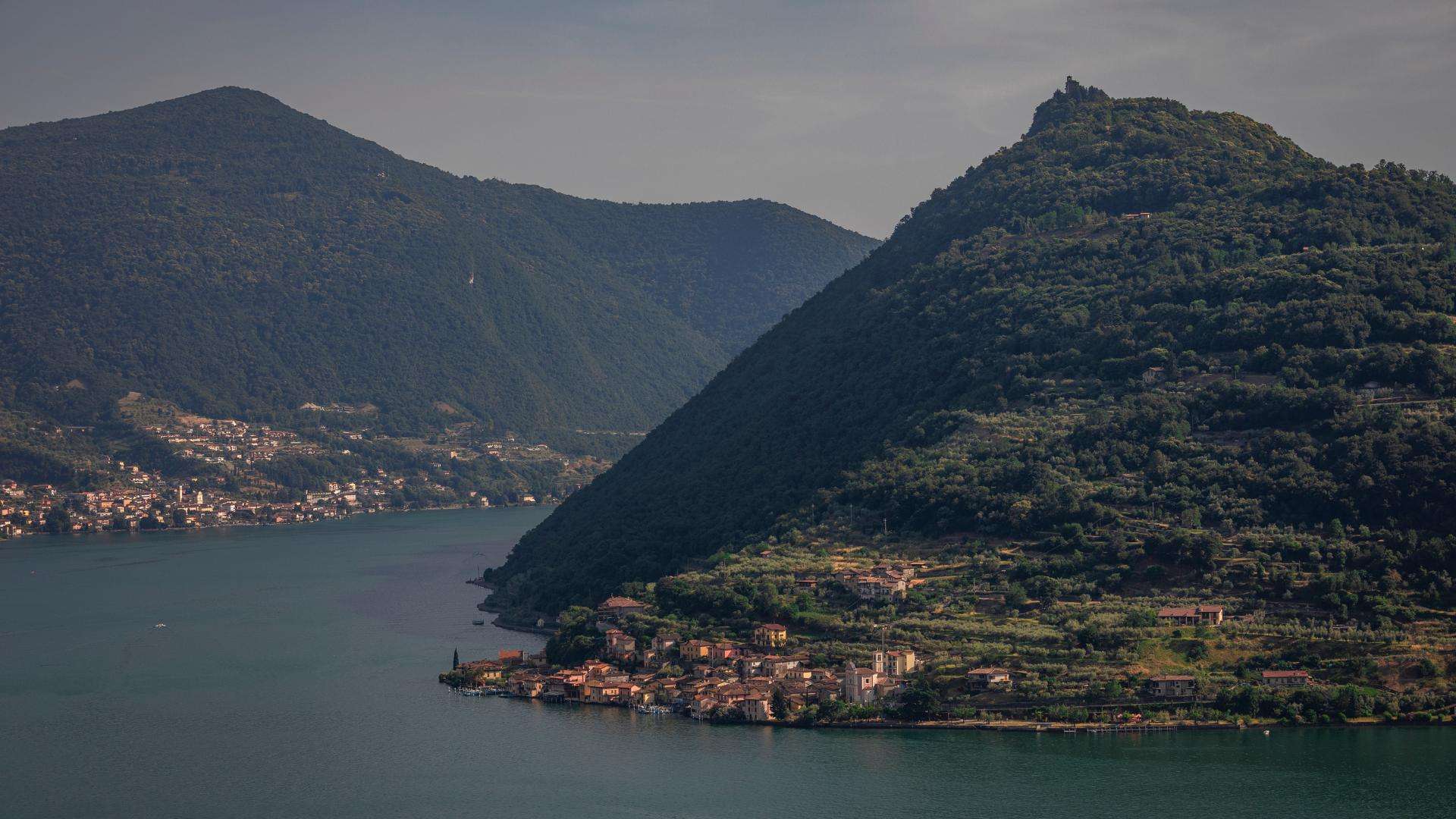 Häuser von Carzano am Fuß der bewaldeten Hänge von Monte Isola