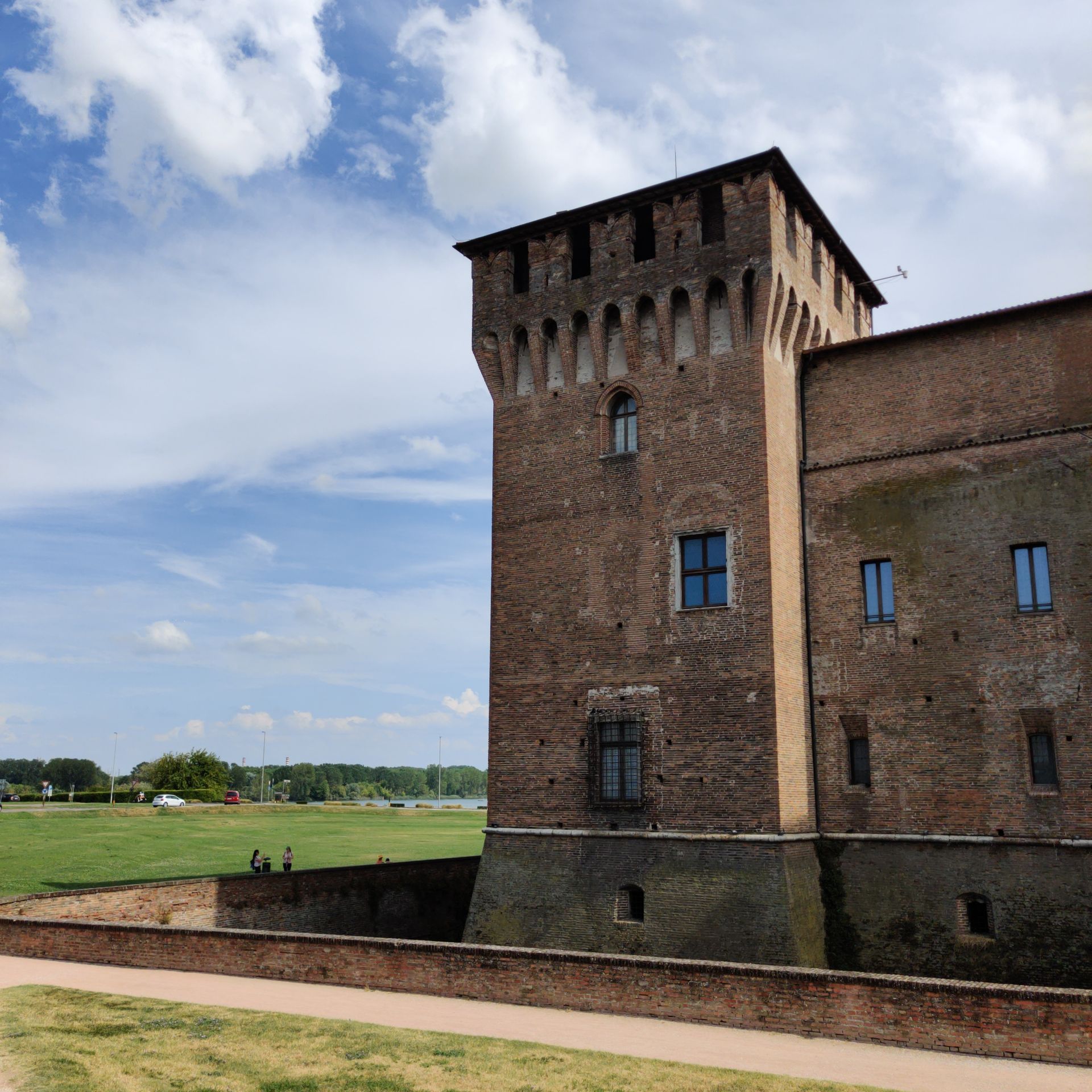 Backsteinturm des Castello di San Giorgio in Mantua mit Zinnenkranz unter blauem Himmel mit Wolken