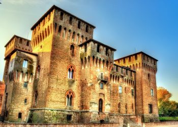 Backsteinfassade des Castello di San Giorgio in Mantua mit Ecktürmen und Zinnen im warmen Abendlicht