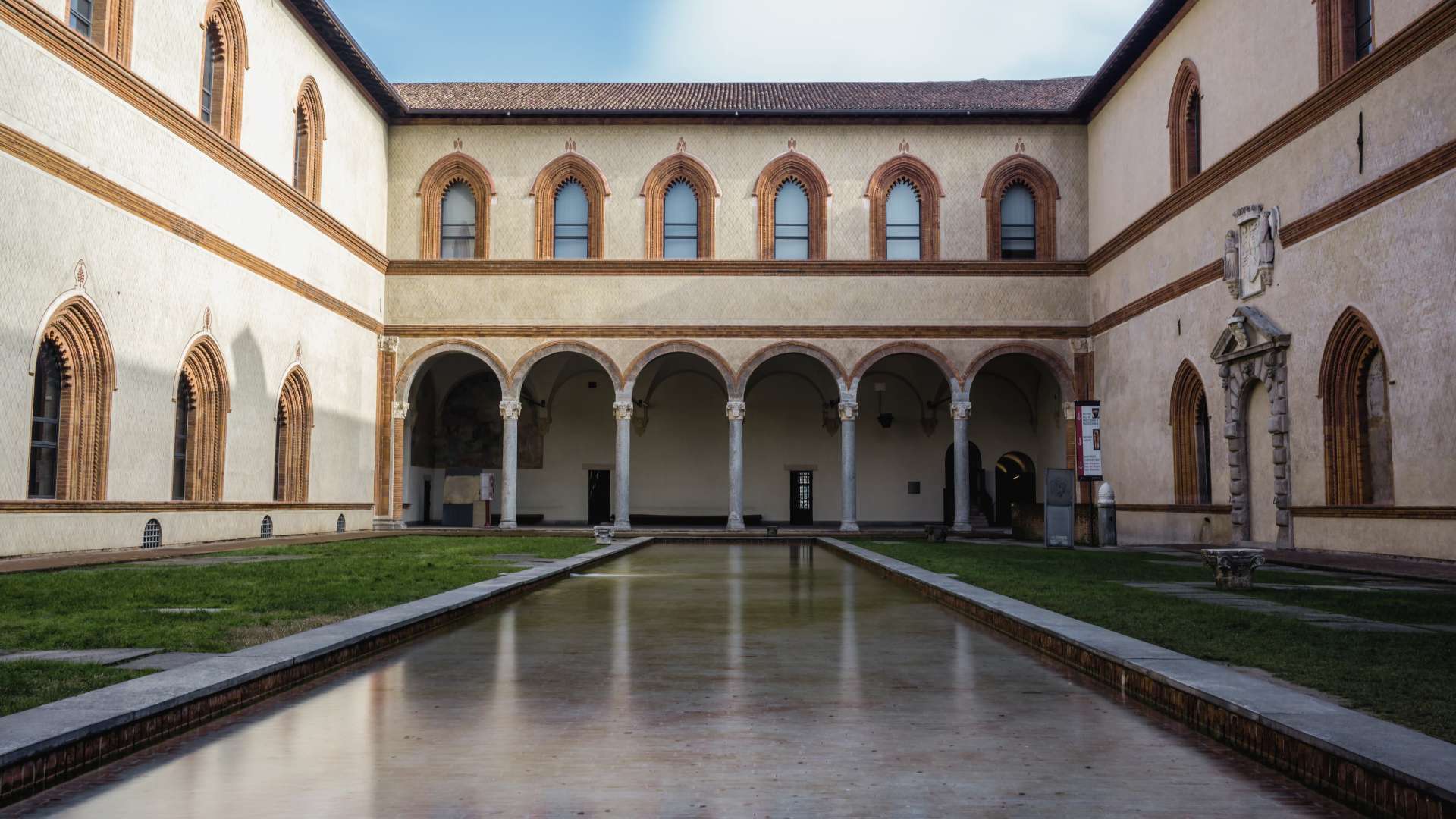 Innenhof der Corte Ducale im Castello Sforzesco mit Arkaden und einem langen, spiegelnden Wasserbecken