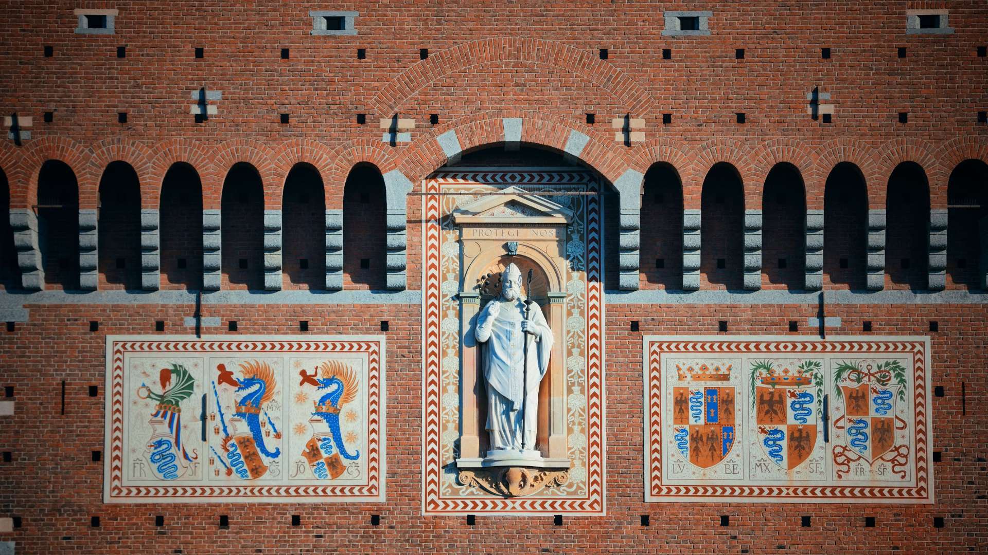 Nische mit der Statue des heiligen Ambrosius zwischen gemalten Sforza-Wappen an der Backsteinfassade des Torre del Filarete
