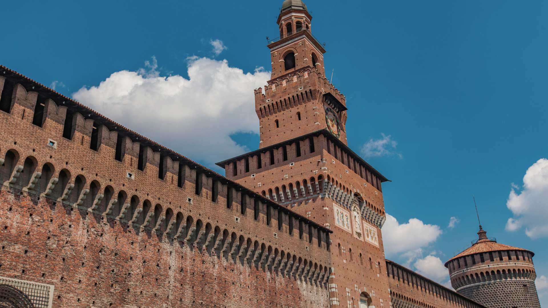 Zinnenbewehrte Backsteinmauer des Castello Sforzesco mit dem Torre del Filarete unter blauem Himmel