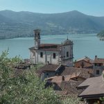 Dorfkirche über den Dächern am Iseosee Dorfkirche mit Glockenturm über Ziegeldächern am Iseosee, vorn Olivenzweige