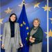 Elly Schlein links neben Elisa Ferreira vor EU-Fahnen bei einem Treffen in Brüssel im Februar 2023