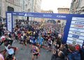 Läuferfeld kurz nach dem Start des Firenze Marathon unter dem Startbogen vor der Marmorfassade des Doms von Florenz