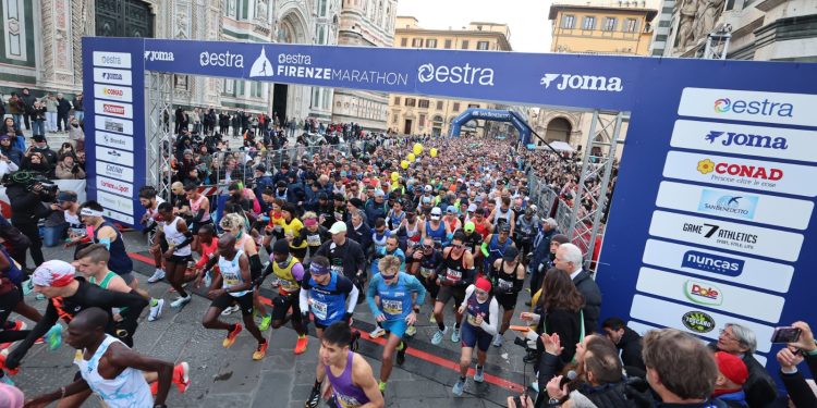 Läuferfeld kurz nach dem Start des Firenze Marathon unter dem Startbogen vor der Marmorfassade des Doms von Florenz