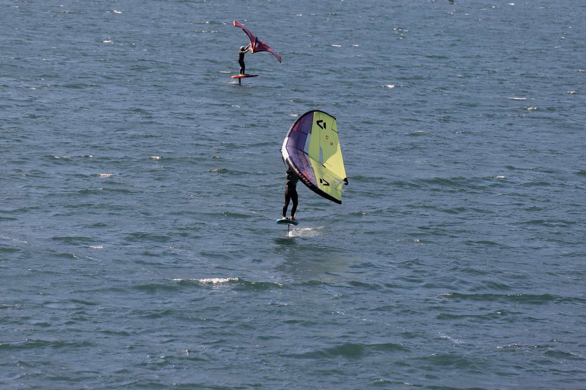 Zwei Wingfoiler gleiten bei kräftigem Wind über den nördlichen Gardasee