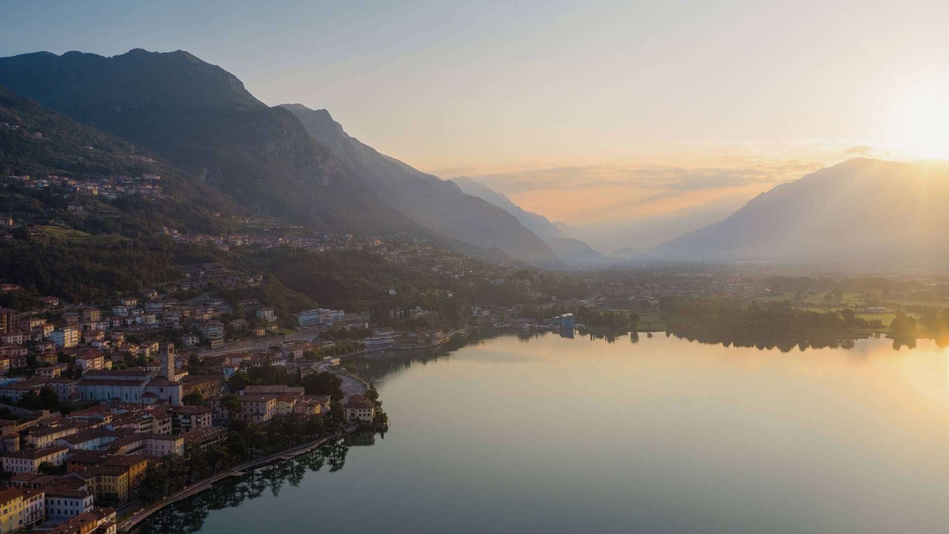 Abendlicht über dem Iseosee Sonnenuntergang über dem Iseosee mit Uferort im Vordergrund und Bergen am Horizont
