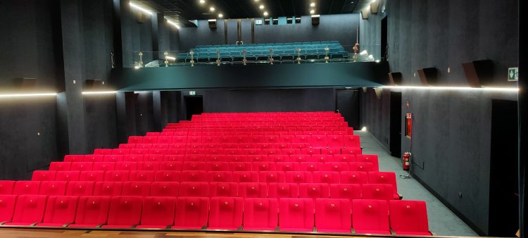 Rote Sitzreihen im leeren Cinema Italia mit einer Galerie im Hintergrund und dunklen Saalwänden