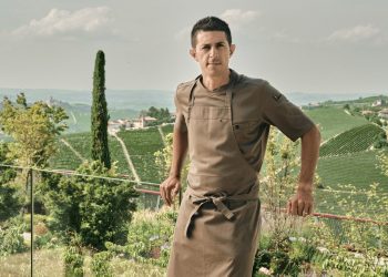 Küchenchef Michelangelo Mammoliti in Kochschürze auf einer Terrasse über den Weinbergen der Langhe