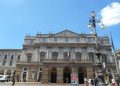 Klassizistische Fassade der Mailänder Scala mit italienischer Flagge und Laterne vor blauem Himmel
