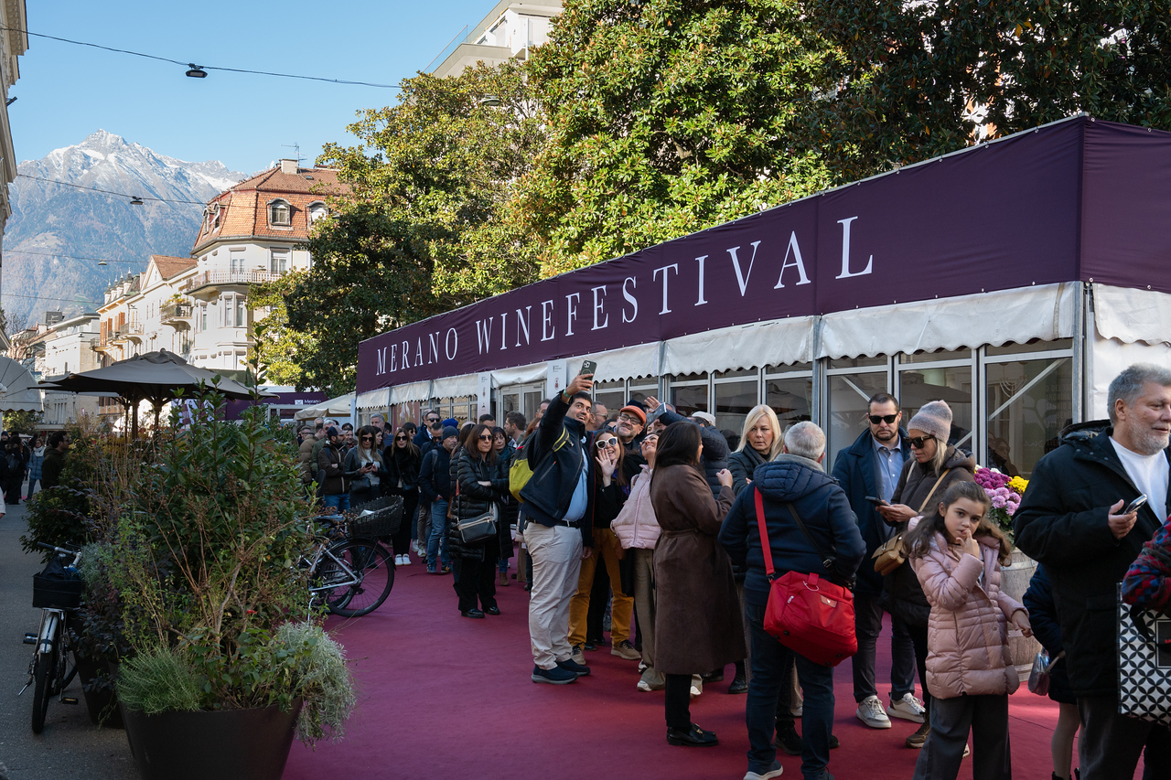 Besucher vor den Zeltbauten der GourmetArena an der Meraner Kurpromenade, im Hintergrund Berge