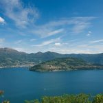 Monte Isola im blauen Iseosee, gesehen zwischen Bäumen am Seeufer