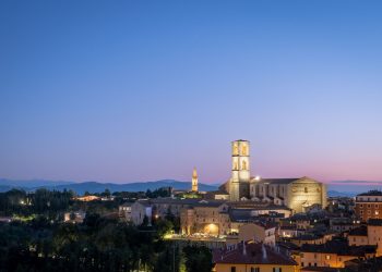 Die Altstadt von Perugia mit beleuchtetem Kirchturm im Abendlicht vor violettem Himmel